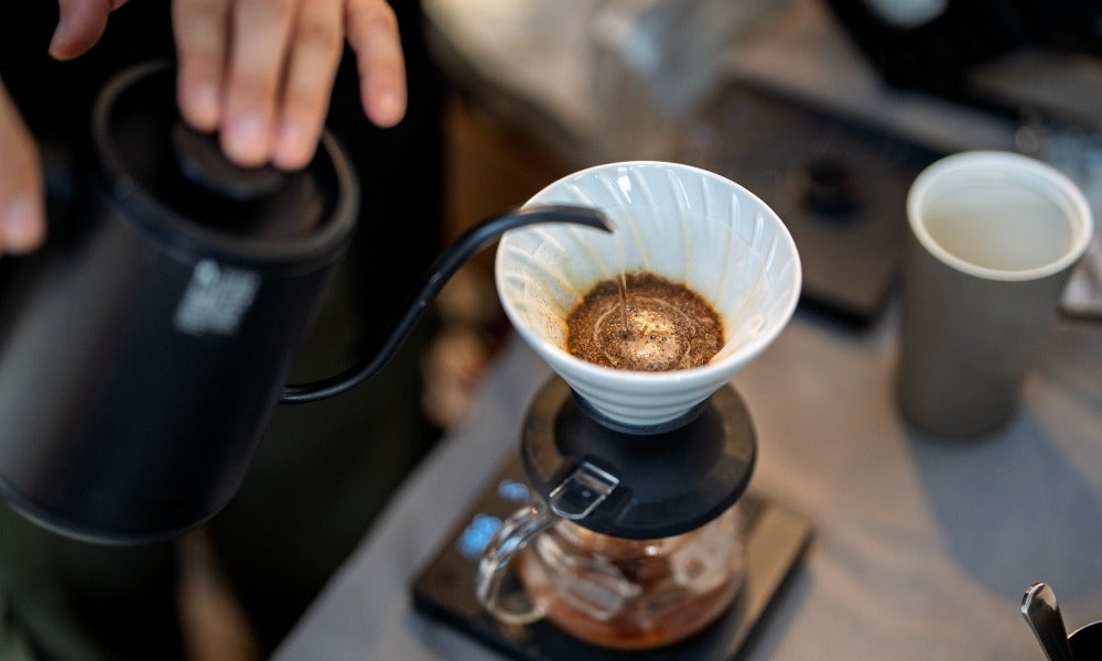 A person brewing coffee with a V60 in the article titled "Can coffee relax you?"