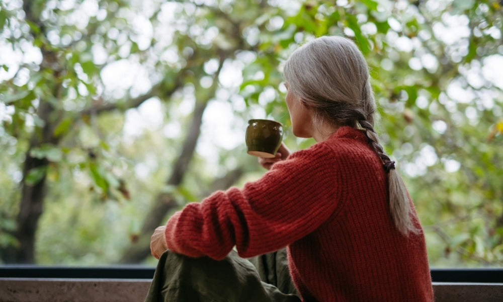 A person drinking coffee while looking out at nature, an example of coffee and mindfulness together.