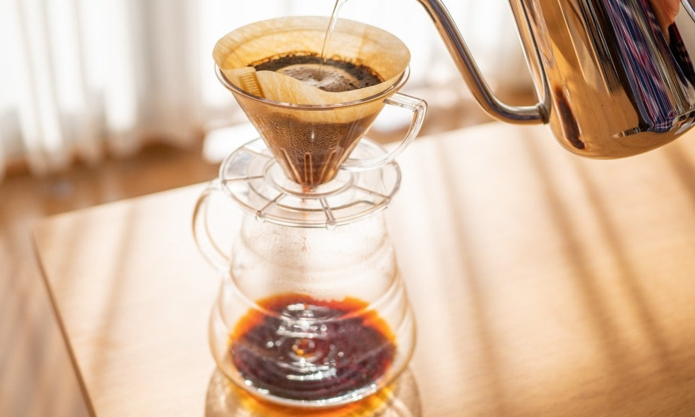 A person brewing wellness coffee using a V60 drip brewer.